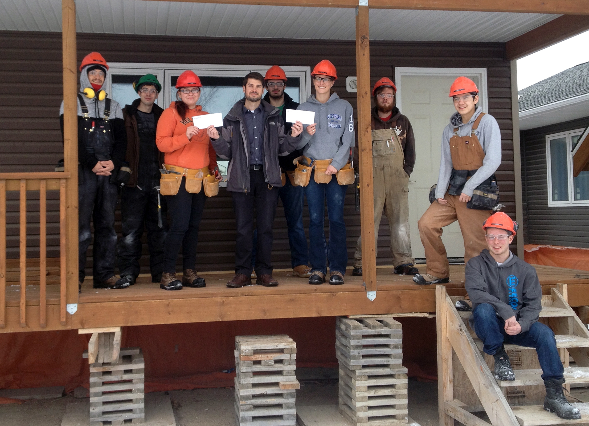 Photo (of Dauphin Co-op building division manager Steve Bunka presenting Nikki Welburn (left) and Kathy Gale (right) with awards, with the rest of the carpentry students outside the home they're building) provided by ACC
